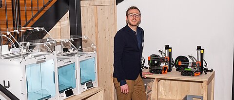 Johannes Zeck, Alumnus der Uni Würzburg, in einem Raum mit 3D-Druckern.