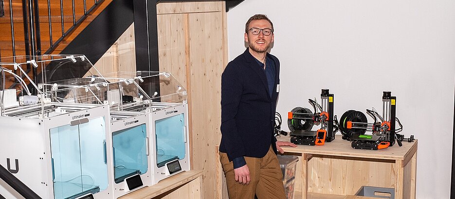 Johannes Zeck, Alumnus der Uni Würzburg, in einem Raum mit 3D-Druckern.