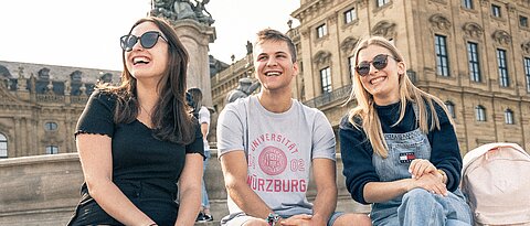 Studierende der JMU vor der Würzburger Residenz. In dem früher fürstbischöflichen Schloss und UNESCO-Welterbe sind unter anderem Philosophie-Lehrstühle und die Altertumswissenschaften der Universität zu Hause.