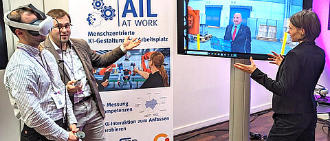 Carolin Wienrich (rechts) und Philipp Krop (Mitte) bei einer Virtual-Reality-Demonstration im Rahmen des AIL-AT-WORK-Projekts. 