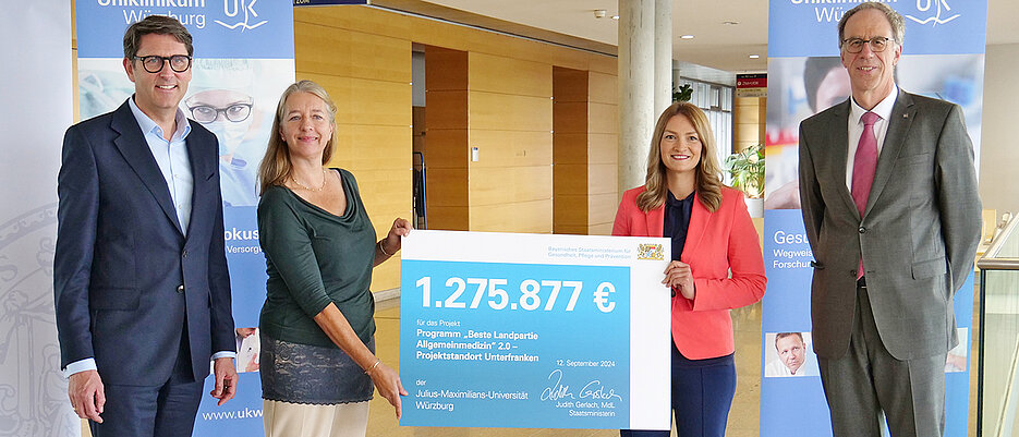 Mit rund 1,2 Millionen Euro unterstützt Bayern das Projekt „Beste Landpartie Allgemeinmedizin“ an der Universität Würzburg. Den symbolischen Scheck hatte Ministerin Judith Gerlach (2.v.r.) bei einem Besuch am UWK dabei. Zu den Empfängern gehören Tim von Oertzen (UKW, links), die Allgemeinmedizinerin Anne Simmenroth sowie Paul Pauli (JMU). 