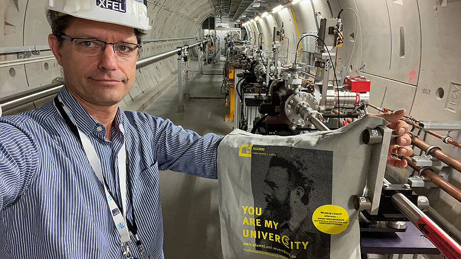 Alumnus Dr. Jan Grünert mit der Uni-Wü-Community-Tasche in den Photonentunneln des Europäischen Röntgenlasers.